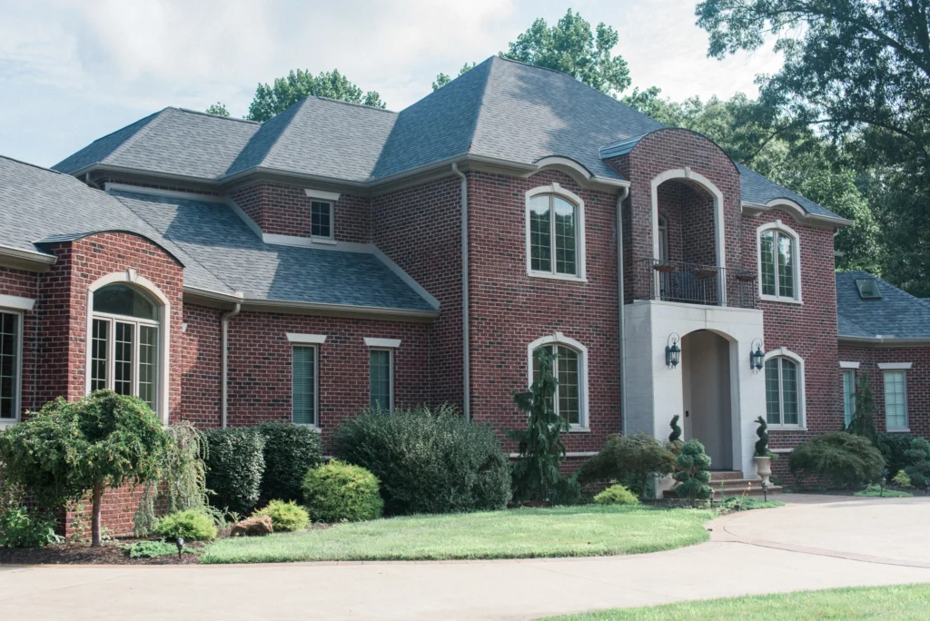 brick home with a new roof built with dark shingles by rapid roofing